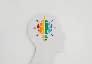 Illustrasjon av en hjerne i profil med fargerike seksjoner, som symboliserer mental helse og ADHD-forekomst hos barn og voksne.