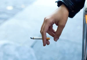 Person som holder en tent sigarett mellom fingrene – illustrerer sammenhengen mellom royking og angst i hverdagslige situasjoner.